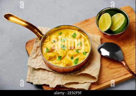 Poulet Korma dans un récipient en cuivre sur une table en béton gris. Cuisine indienne plat de cari à la viande avec masala au lait de coco. Cuisine asiatique Banque D'Images