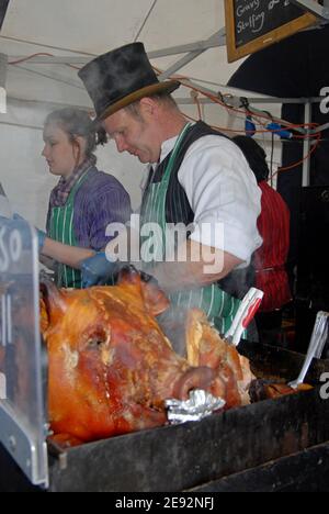 A Butcher sert du rôti de porc aux visiteurs du marché de Noël victorien de Worcester, décembre 2007 Banque D'Images