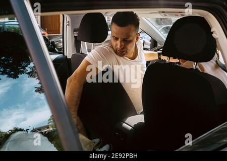 Homme mûr regardant en arrière en étant assis dans une voiture électrique Banque D'Images