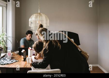 Mère embrassant son fils sur une table à manger à la maison Banque D'Images