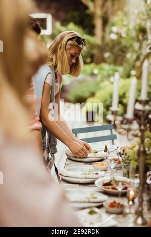 Une adolescente organise une assiette sur la table pour le dîner Banque D'Images