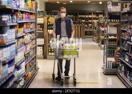 Photo du dossier datée du 24/7/2020 d'un acheteur portant un masque facial dans un supermarché de l'est de Londres. Les supermarchés ont connu une forte hausse des ventes, les systèmes de hiérarchisation et les nouveaux blocages nationaux ayant contribué à augmenter les ventes de 12.2 % au cours des 12 semaines jusqu'en janvier 24, selon les dernières données de Kantar Grocer. Date de publication : mardi 2 février 2021. Banque D'Images