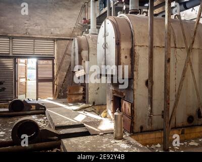 Ancienne fonte et acier industriel huile et charbon millésime chaudières de chauffage dans la chaufferie sombre et sombre abandonnée avec les tuyaux et les ventilateurs sont sales Banque D'Images