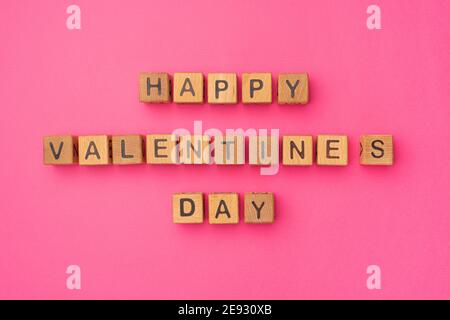 Cubes en bois avec l'expression « Happy Valentine's Day » sur fond rose coloré vide. Les mots d'amour sont faits de lettres de bois pour la Saint-Valentin et pour votre petite amie, petit ami, femme, mari saluant carte postale romantique. Flat lay, vue de dessus Banque D'Images