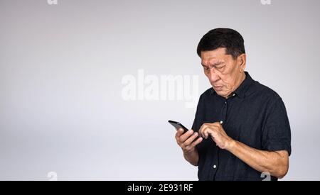 Problème de vue de l'homme asiatique senior utilisant un téléphone portable Banque D'Images