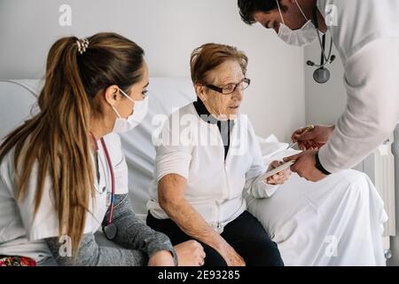 Femme âgée assise sur un canapé à la maison et signe médical contrat de procédure de diagnostic par les médecins Banque D'Images