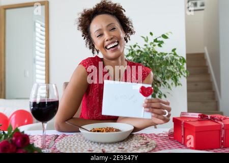 Portrait d'une femme afro-américaine tenant une carte de Saint-Valentin vidéo à la maison Banque D'Images