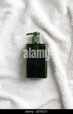 Bouteille de distributeur de savon vert ou de shampooing sur la vue de dessus de serviette blanche. Maquillage, marque de produits cosmétiques naturels biologiques SPA. Banque D'Images