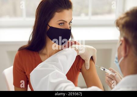 Femme dans le masque de protection médical se faire injecter dans la vaccination de bras contre 19-ncov Banque D'Images