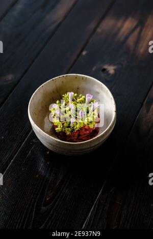 Tartare de viande rouge décorée et plaquée de fleurs et jardin vert Banque D'Images