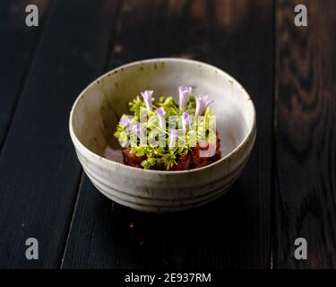 Tartare de viande rouge décorée et plaquée de fleurs et jardin vert Banque D'Images