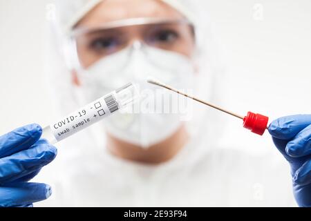 Medical UK Healthcare technologue tenant le kit de prélèvement d'écouvillons COVID-19, en blanc Gant masque de protection PPE, tube à essai pour la prise OP NP patien Banque D'Images