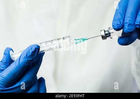 Infirmier de laboratoire médical NHS, technicien, insertion de l'aiguille de la seringue dans un flacon en verre, injection de médicament COVID-19, remède contre l'infection par le virus, Banque D'Images