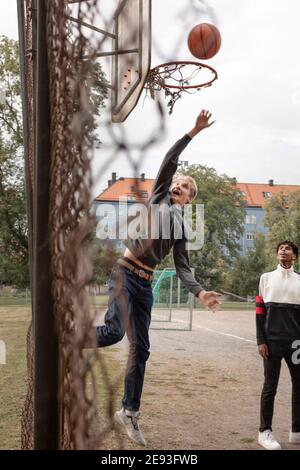 Un adolescent lance une balle dans un panier de basket-ball Banque D'Images