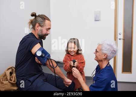 Médecin examinant le père et les filles dans le centre de santé Banque D'Images