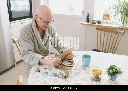 Homme assis à table et ayant le chat vidéo sur tablette Banque D'Images