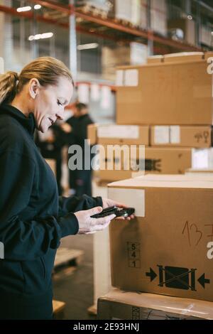 Une femme entrepreneur qui lit avec lecteur de code-barres à l'entrepôt logistique Banque D'Images