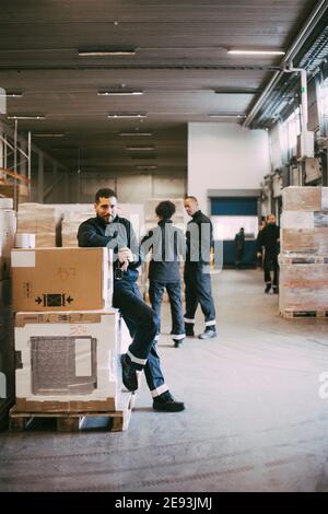 Homme d'affaires s'appuyant sur des conteneurs de boîtes dans l'entrepôt