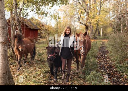 Femme marchant avec des chevaux sur la route de campagne Banque D'Images