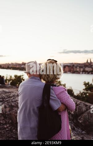 Homme âgé embrassant la femme en se tenant sur le rocher au bord du lac Banque D'Images