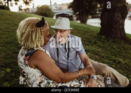 Couple hétérosexuel se regardant les uns les autres tout en étant assis sur l'herbe Banque D'Images