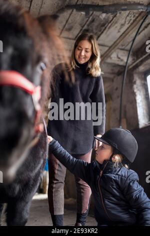 Mère avec fille préparant le poney pour le tour Banque D'Images