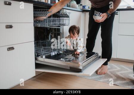 Père avec tout-petit mettant la vaisselle au lave-vaisselle Banque D'Images