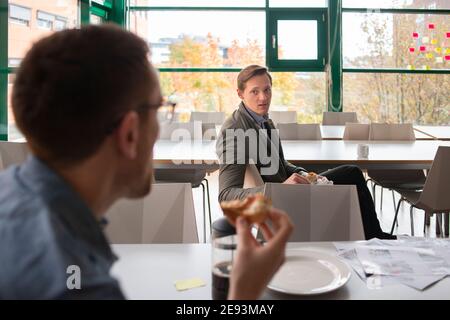 Hommes d'affaires qui parlent à la cafétéria à l'heure du déjeuner Banque D'Images
