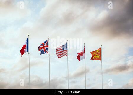 Drapeaux de la Seconde Guerre mondiale du jour J des nations des forces militaires alliées Canada France Grande-Bretagne et Amérique en vol au coucher du soleil Ville française Arramanches Gold B. Banque D'Images