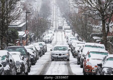 Une voiture traversant une rue en terrasse sous la neige Tempête dans le quartier de Crouch End alors que la capitale London est en vie une couverture rare de neige Banque D'Images