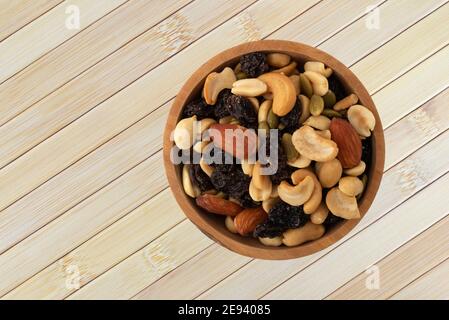 Vue de dessus d'un assortiment de noix et de fruits secs dans un bol en bois sur un placaret en bois. Banque D'Images