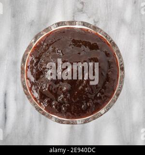 Vue de dessus d'un bol en verre rempli de beurre de prune sur un plan d'examen en marbre gris. Banque D'Images