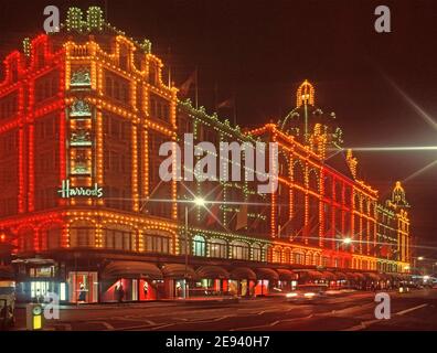 Vue nocturne des années 1990 insolite scène de rue de l'éclairage coloré allumé Célèbre façade avant emblématique du grand magasin de luxe Harrods Bâtiment d'affaires dominant les magasins sur Brompton Road Knightsbridge Londres, Angleterre Image d'archives historiques des années 1980 au Royaume-Uni Banque D'Images