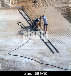 Archiver la vue des années 1980 sur un homme de jour très chaud à Travail sous le soleil maltais travail au fond de calcaire poussiéreux exploitation d'une carrière minière en fonte ouverte utilisant une machine de coupe à disque sur rail mobile, vers l'arrière et vers l'avant, sciant la pierre molle roche à découper et blocs de forme pour les années 80 Chantiers de construction sur l'île de Malte archives historiques Image juin 1981 Banque D'Images