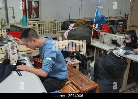 (210202) -- FUZHOU, 2 février 2021 (Xinhua) -- Congcong, fils de Huang Hailong, accompagne ses parents dans une usine de vêtements de Shishi, dans la province du Fujian, dans le sud-est de la Chine, qui fabrique des manches et des oreillers pour leurs proches, le 26 janvier 2021. Suite à la résurgence sporadique des cas de COVID-19, de nombreux endroits en Chine ont encouragé les résidents et les travailleurs migrants à rester mis en place pour célébrer le Festival du printemps, pour réduire le flux de personnel et freiner la propagation du coronavirus pendant la période des fêtes. Huang Hailong, un travailleur migrant de Shishi, a déclaré que ce serait sa première fois dans les années passées t Banque D'Images