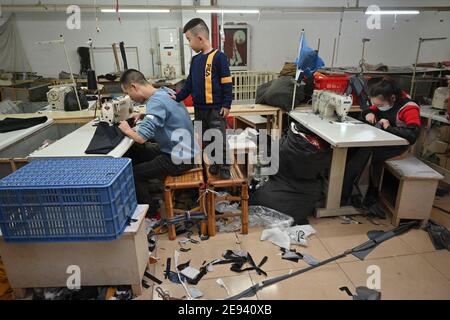 (210202) -- FUZHOU, 2 février 2021 (Xinhua) -- Congcong, fils de Huang Hailong, accompagne ses parents dans une usine de vêtements de Shishi, dans la province du Fujian, dans le sud-est de la Chine, qui fabrique des manches et des oreillers pour leurs proches, le 26 janvier 2021. Suite à la résurgence sporadique des cas de COVID-19, de nombreux endroits en Chine ont encouragé les résidents et les travailleurs migrants à rester mis en place pour célébrer le Festival du printemps, pour réduire le flux de personnel et freiner la propagation du coronavirus pendant la période des fêtes. Huang Hailong, un travailleur migrant de Shishi, a déclaré que ce serait sa première fois dans les années passées t Banque D'Images