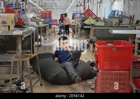 (210202) -- FUZHOU, 2 février 2021 (Xinhua) -- Congcong, fils de Huang Hailong, joue sur le paquet de cadeau que ses parents ont fait pour leurs proches dans une usine de vêtements à Shishi, dans la province du Fujian, dans le sud-est de la Chine, le 26 janvier 2021. Suite à la résurgence sporadique des cas de COVID-19, de nombreux endroits en Chine ont encouragé les résidents et les travailleurs migrants à rester mis en place pour célébrer le Festival du printemps, pour réduire le flux de personnel et freiner la propagation du coronavirus pendant la période des fêtes. Huang Hailong, un travailleur migrant de Shishi, a déclaré que ce serait sa première fois au cours des dernières années à cracher Banque D'Images