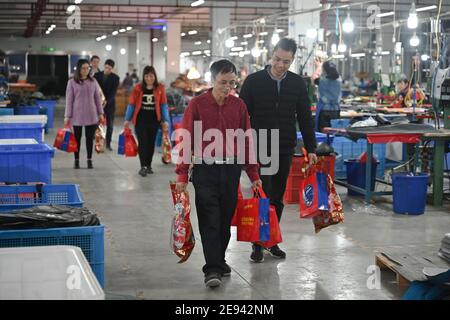 (210202) -- FUZHOU, 2 février 2021 (Xinhua) -- Zhang Liangguo (L, avant) le transport des kits du festival est effectué à Wellgreen Outdoor Co., Ltd., dans le comté de Minhou, à Fuzhou, dans la province de Fujian, dans le sud-est de la Chine, le 1er février 2021. Suite à la résurgence sporadique des cas de COVID-19, de nombreux endroits en Chine ont encouragé les résidents et les travailleurs migrants à rester mis en place pour célébrer le Festival du printemps, pour réduire le flux de personnel et freiner la propagation du coronavirus pendant la période des fêtes. Dans le comté de Minhou à Fuzhou, dans la province de Fujian, une usine d'équipement de plein air a donné des kits cadeaux du nouvel an à plus de Banque D'Images