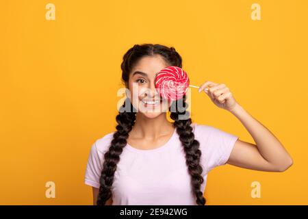 Femme indienne tenant une lollipop, couvrant un oeil avec des bonbons Banque D'Images