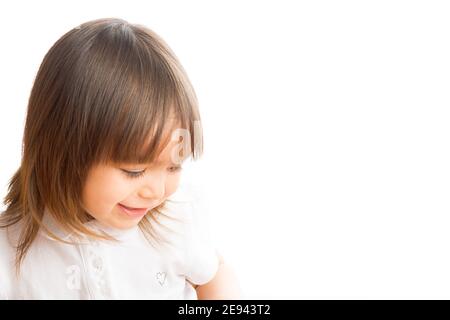 Une fille de deux ans souriant regarde vers le bas. Banque D'Images