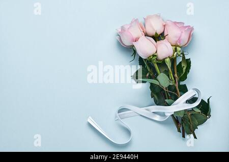 Roses roses roses bouquet de fleurs avec ruban sur fond bleu. Modèle de carte de vœux avec espace de copie Banque D'Images