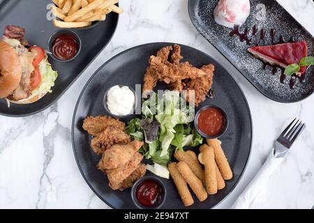 Sheffield, Royaume-Uni - 03 août 2017 : poulet frit du sud, assortiment de beignets de mozarella, cheeseburger et frites et cheesecake à OHM, Fitzwilliam Street Banque D'Images