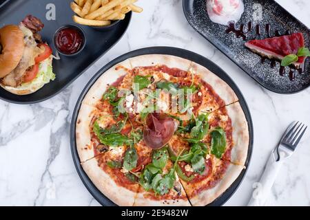 Sheffield, Royaume-Uni - 03 août 2017 : pizza au salami pepperoni et à la roquette, cheeseburger et frites et cheesecake à OHM, Fitzwilliam Street Banque D'Images