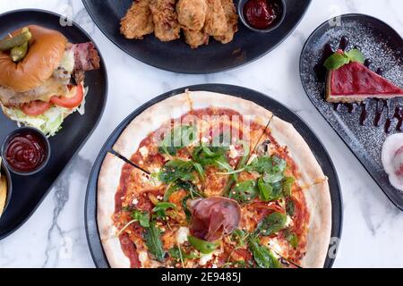 Sheffield, Royaume-Uni - 03 août 2017 : pizza à la roquette et au salami pepperoni, SFC, cheeseburger et frites et cheesecake à OHM, Fitzwilliam Street Banque D'Images