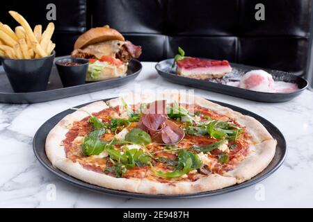 Sheffield, Royaume-Uni - 03 août 2017 : pizza au salami pepperoni et à la roquette, cheeseburger et frites et cheesecake à OHM, Fitzwilliam Street Banque D'Images