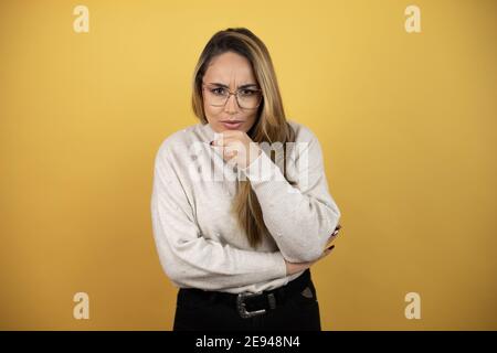 Jolie femme avec de longs cheveux toussant avec la main suivante à la bouche contre le mur jaune Banque D'Images