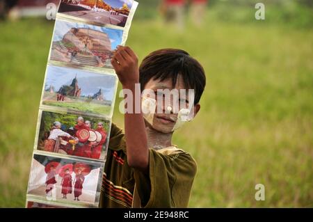 BAGAN, MYANMAR - 18 NOVEMBRE 2015: Petit garçon ethnique montrant des photos colorées, adorable garçon asiatique avec peinture faciale à tanaka montrant un collage de pH coloré Banque D'Images