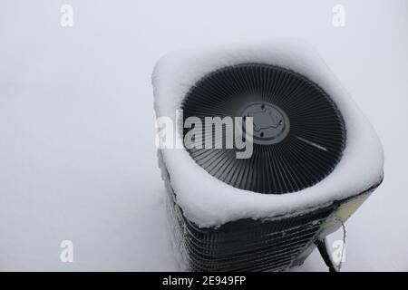 Unité de climatisation extérieure gelée après une tempête de neige et de verglas en hiver. Banque D'Images