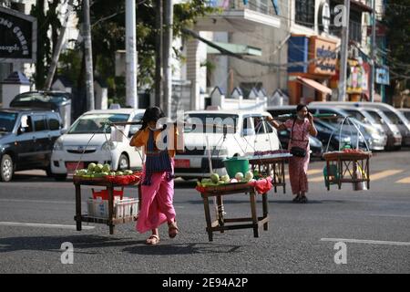 Yangon, Myanmar. 2 février 2021. Des vendeurs traversent la rue à Yangon, Myanmar, le 2 février 2021. Une majorité des ministres régionaux et des chefs d'État ont été libérés mardi après la détention d'une journée de l'armée, a déclaré un haut responsable militaire à Xinhua. Aung San Suu Kyi, conseillère d'État du Myanmar, le président U Win Myint et d'autres hauts fonctionnaires de la Ligue nationale pour la démocratie (NLD) au pouvoir ont été arrêtés par les militaires au début de lundi. Le Bureau du Président a déclaré l'état d'urgence pendant un an et le pouvoir de l'État a été remis au Commandant en chef de la Défense Servi Banque D'Images