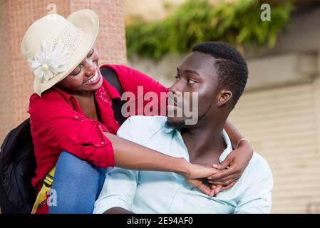 Jeune heureux couple touristique assis dehors s'embrassant mutuellement. Banque D'Images